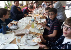 uczniowie jedzą pizzę w pizzerii